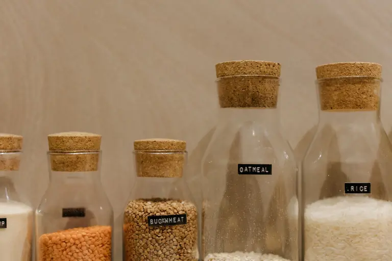 Close-up of various grains in labeled glass jars for kitchen storage.