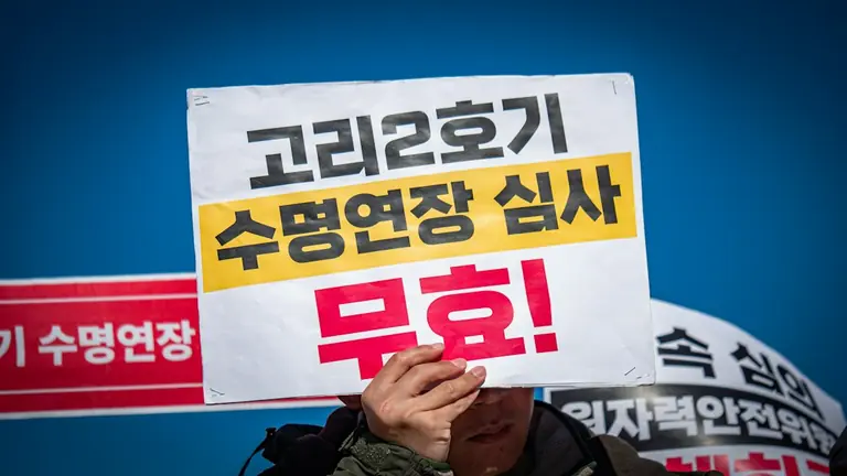 Person holds sign protesting nuclear power plant operation.