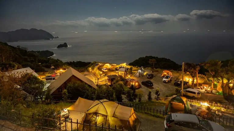 a night time view of a camp site with a view of the ocean