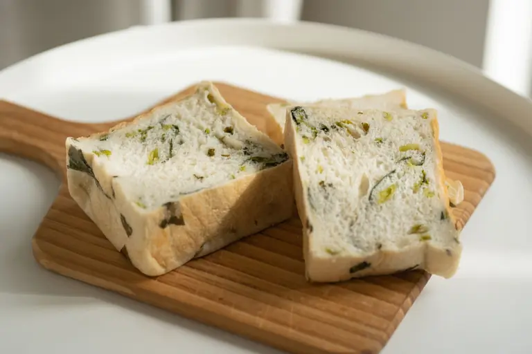 Close-up of herb-infused bread slices on wooden board, showcasing fresh ingredients.
