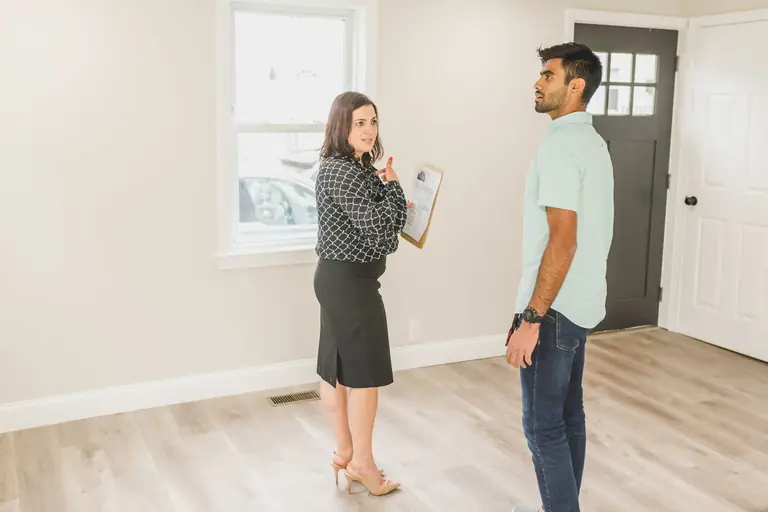 Real estate agent showing a modern home interior to a potential buyer.