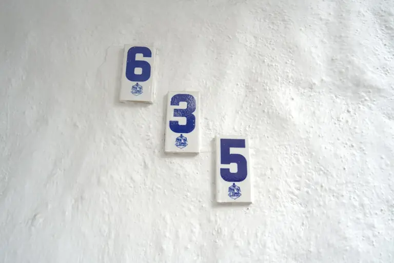 Blue numbers 6, 3, 5 on a white textured wall.