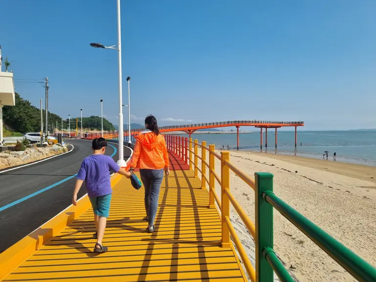 Colorful boardwalk along the serene beach in Hongseong, South Korea, featuring people leisurely walking.