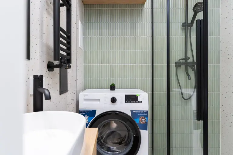Sleek bathroom design featuring a washing machine, shower, and basin in Kraków.