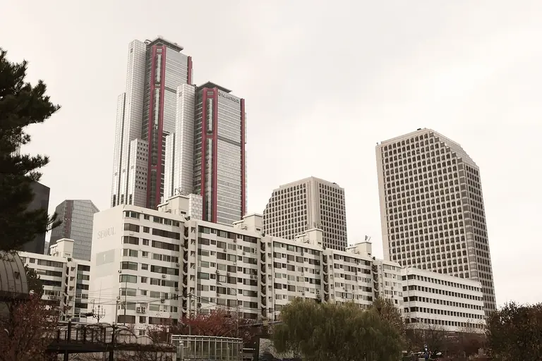 View of modern skyscrapers against a cloudy sky in downtown Seoul during fall.