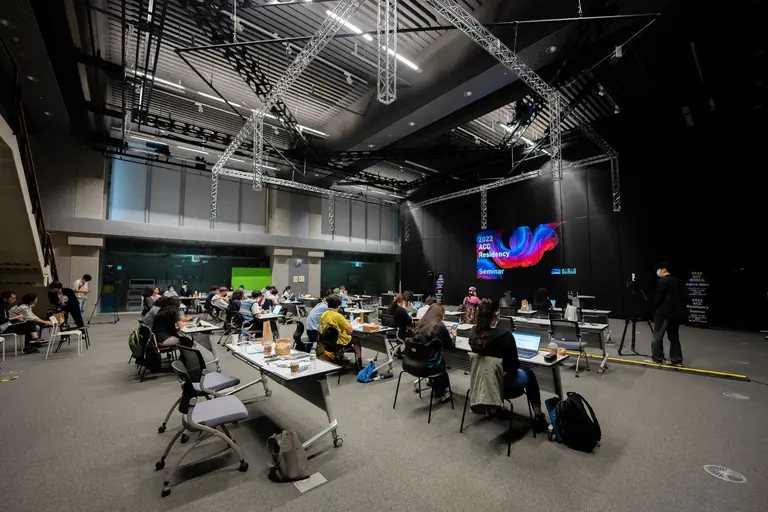 A diverse group attending an educational seminar with screens and seating indoors, highlighting collaboration.
