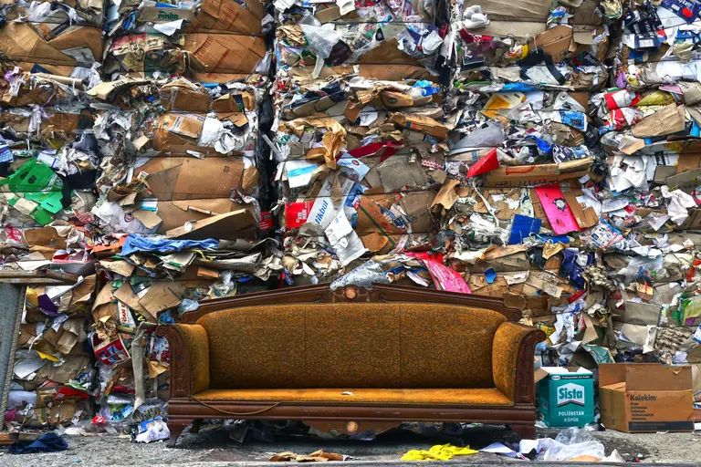 A vintage sofa placed against a backdrop of compressed cardboard waste in Istanbul.