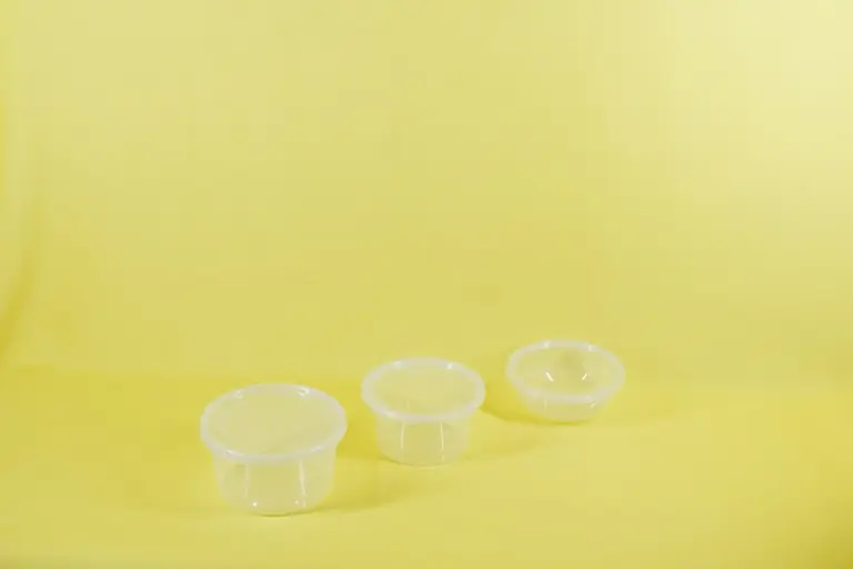 three plastic containers sitting on a yellow surface