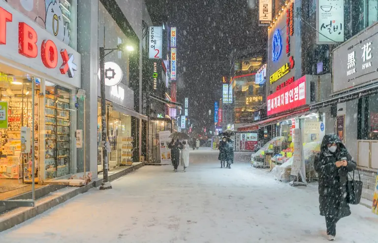 a woman walking down a snow covered street