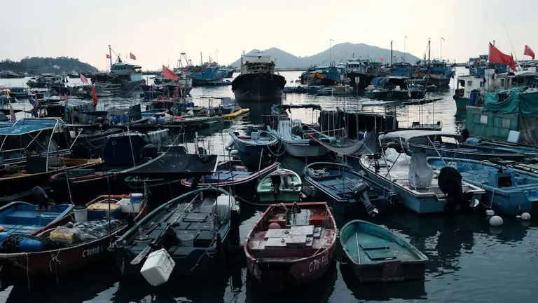 Fishing boats docked in a busy harbor at dusk.