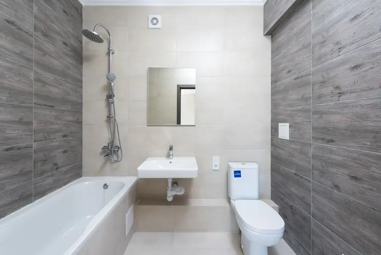 A contemporary bathroom features a bathtub, sink, and toilet with wood accents.