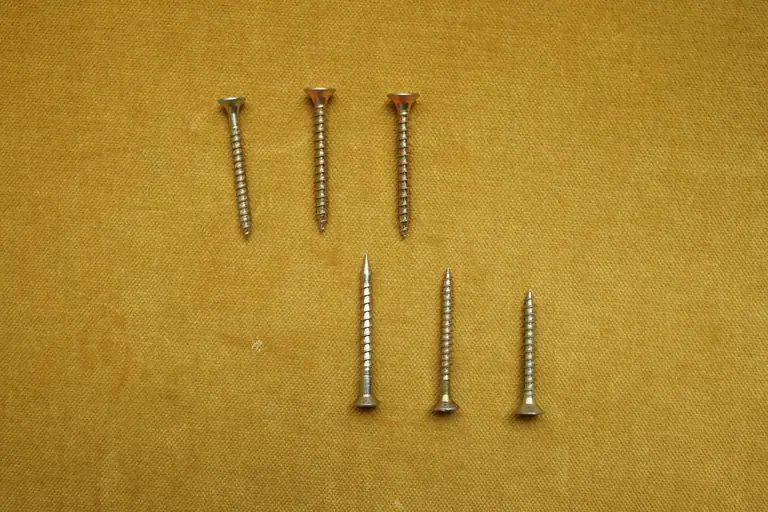 A close-up of seven silver screws arranged on a textured yellow surface.