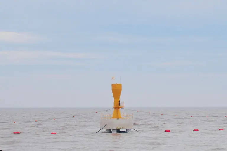 Yellow buoy marking navigation point in the vast, tranquil sea under a clear blue sky.