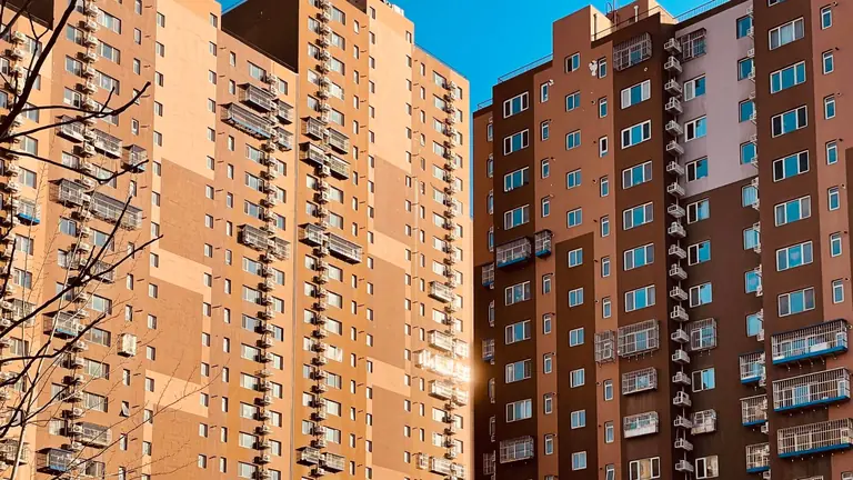 Modern high-rise urban apartment buildings with sunlit facades and clear blue sky.
