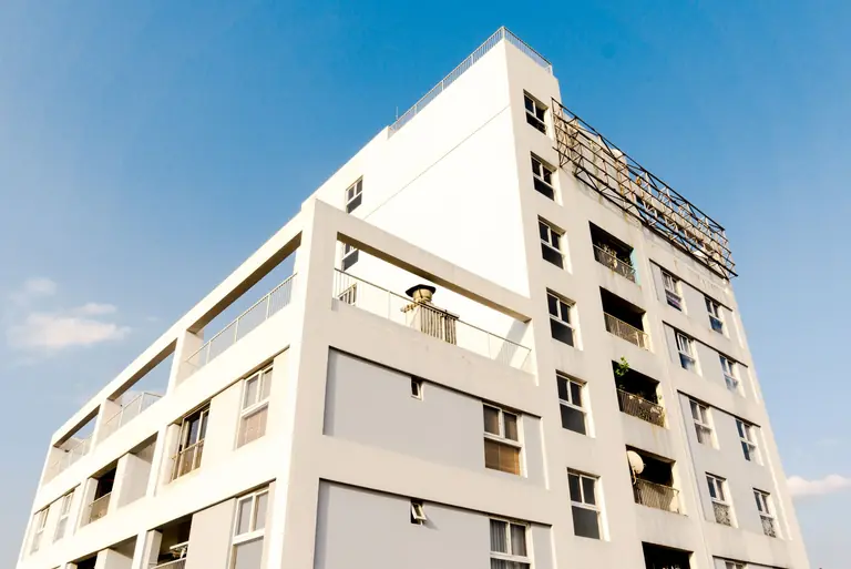 A modern apartment building with balconies against a clear blue sky.