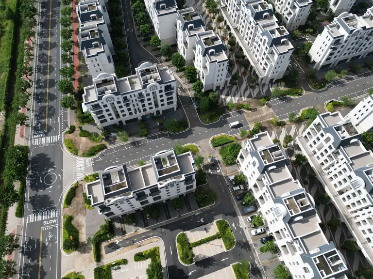 Aerial view of modern white apartment buildings in Đồng Nai, Vietnam, surrounded by lush greenery and roads.