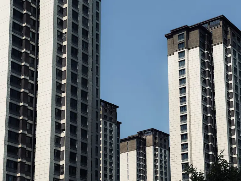 A cluster of modern high-rise buildings against a bright blue sky, showcasing urban architecture.