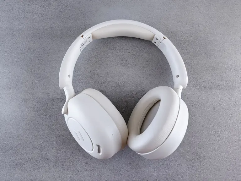 Close-up of sleek white wireless headphones on a textured gray surface. Ideal for audio enthusiasts.