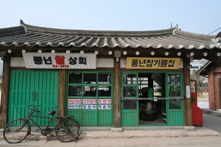 Old storefront with bicycle and korean signage.