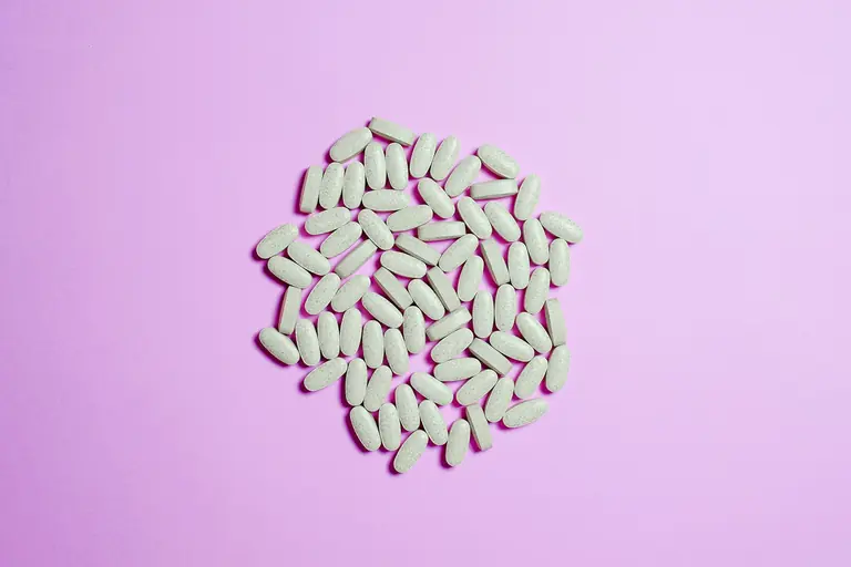 A cluster of white pills on a purple surface, highlighting pharmaceutical themes.