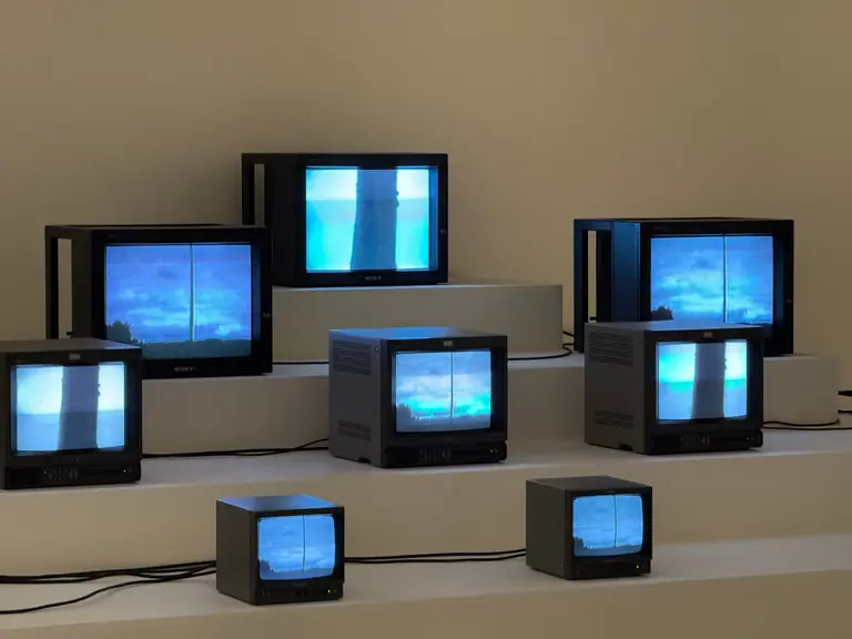 Artistic arrangement of vintage TVs displaying static and blue screens in a minimalist setting.
