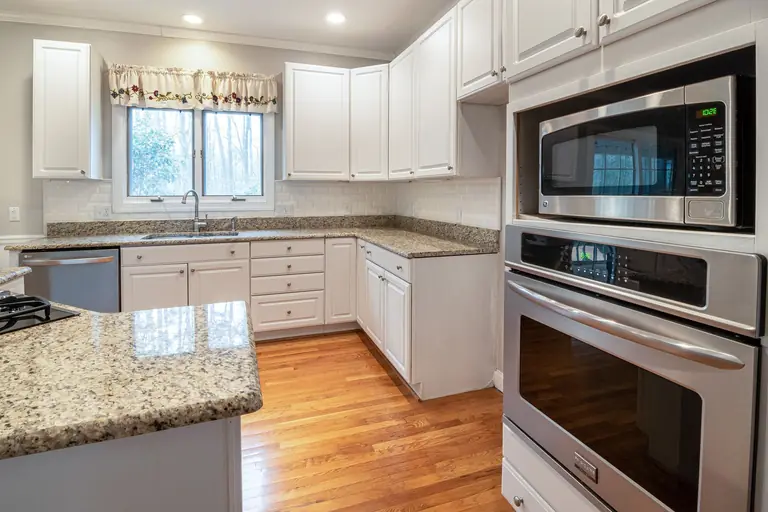 Spacious modern kitchen with white cabinets and granite countertops.
