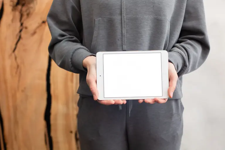 Close-up of a person in grey holding a tablet with a blank screen, ready for customization.
