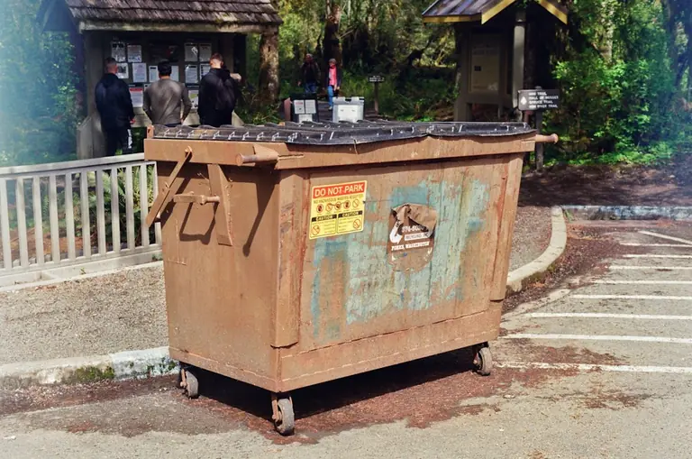 a trash can sitting in the middle of a parking lot