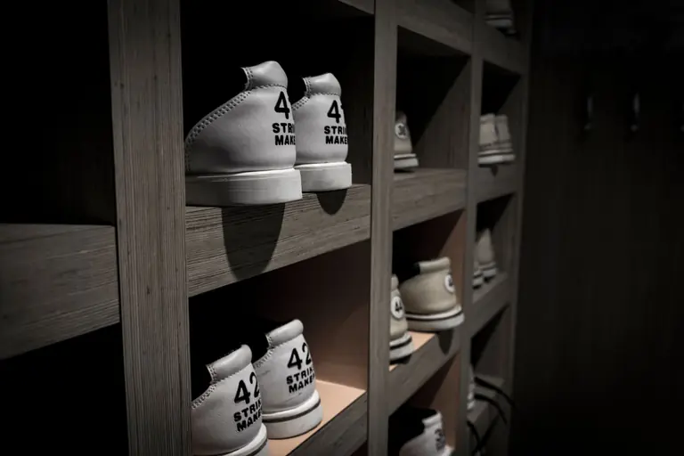 White sneakers labeled with '42' are neatly organized on wooden shelves in a dimly lit room.