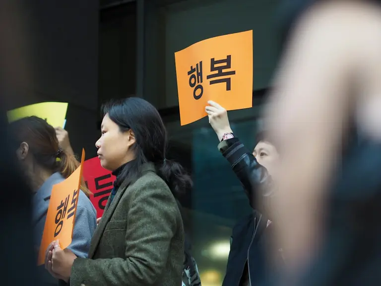 women holding Hangul banners