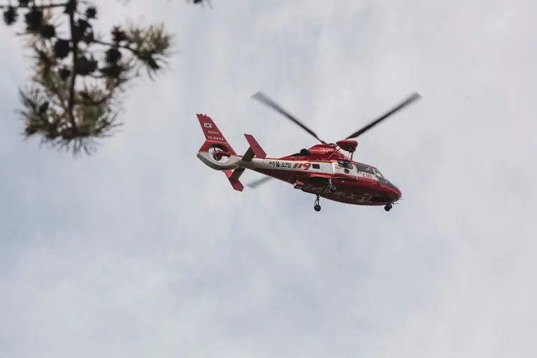 Red and white rescue helicopter flying in the sky, captured outdoors.
