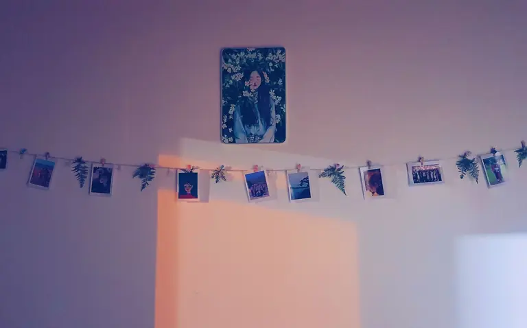 Aesthetic wall art with hanging string photos and botanical accents.