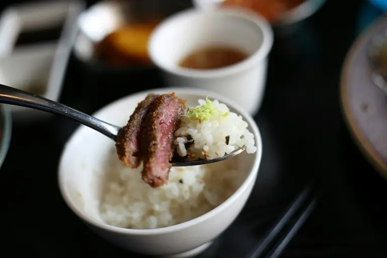 Spoonful of rice with sliced meat and garnish