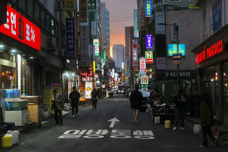 Street scene with neon signs and pedestrians at dusk
