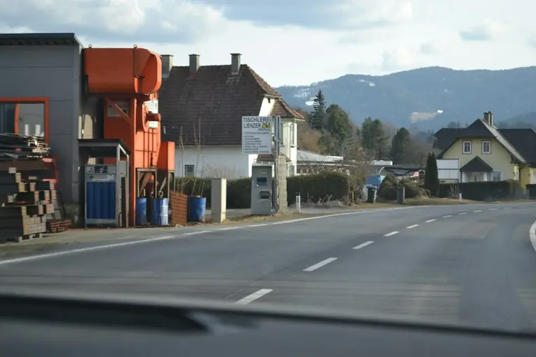 Roadside industrial buildings with houses and mountains beyond