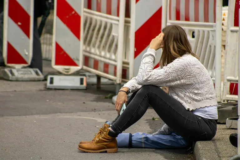 A woman sitting on the ground with her head in her hands