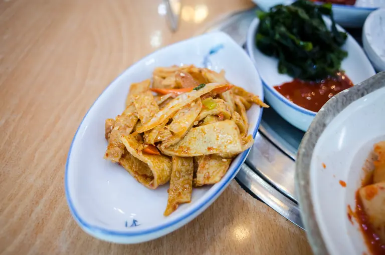 Close-up of a Korean fish cake dish served in a white bowl on a wooden table.