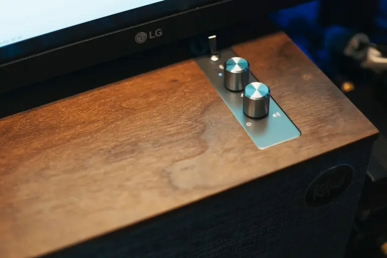 Close-up of a modern audio control panel with knobs on a wooden surface, ideal for sound setups.