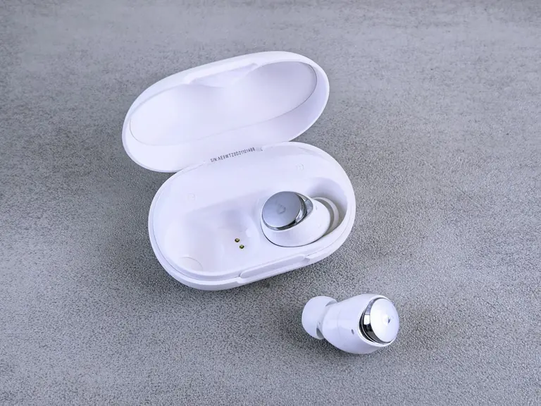 White wireless earbuds with charging case on gray background