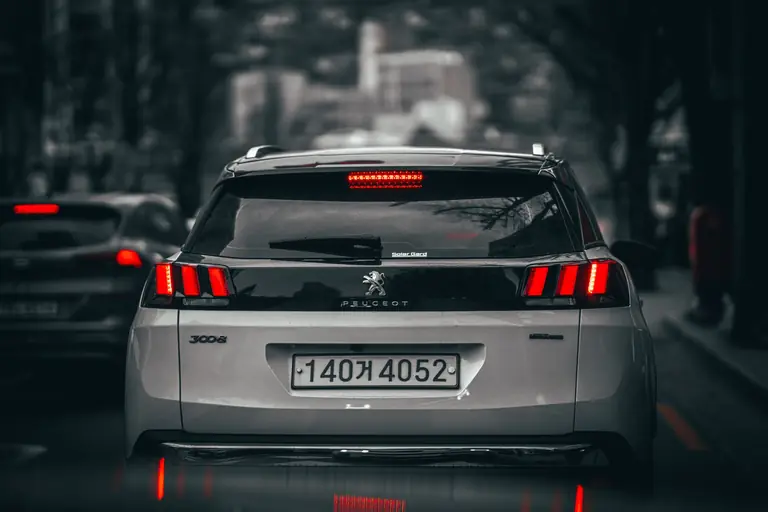 Rear view of a modern SUV on busy city streets, showcasing taillights and urban landscape.