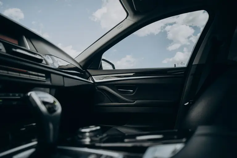 Sleek car interior showcasing gearshift and view through window with clear sky.