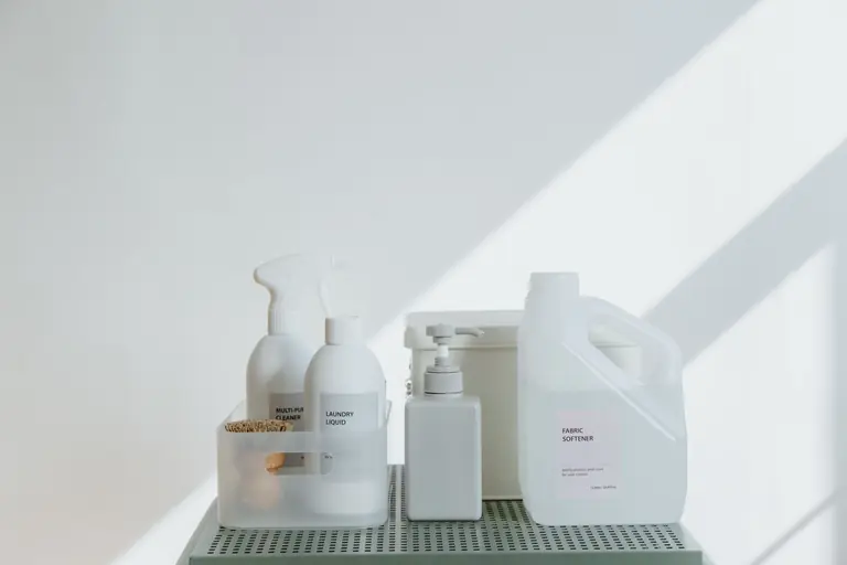 Clean and simple display of various cleaning products in soft lighting on a white background.