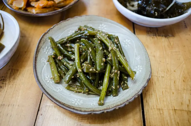 Delicious seasoned vegetables garnished with sesame seeds on a ceramic plate.