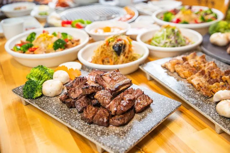 A tempting array of Asian dishes including grilled meat and vegetables served in a welcoming indoor setting.