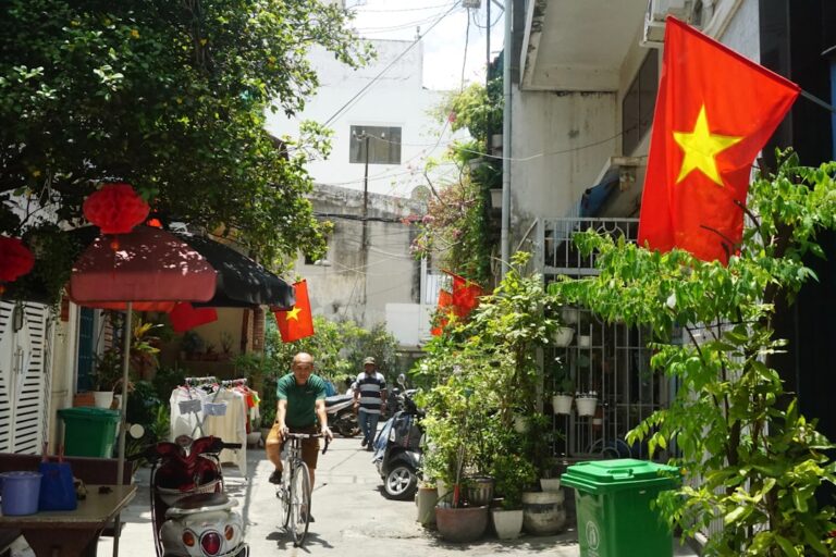 Vietnamese flag flies above a street with cyclists.